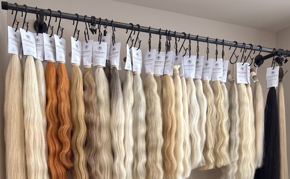 Premium raw Slavic hair extensions on a display rack in various shades