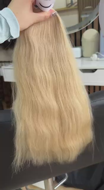 Video showing the flexibility and shine of a 50 cm (20 inch) premium raw Slavic wavy hair extension in cold-bleached Honey Blonde color