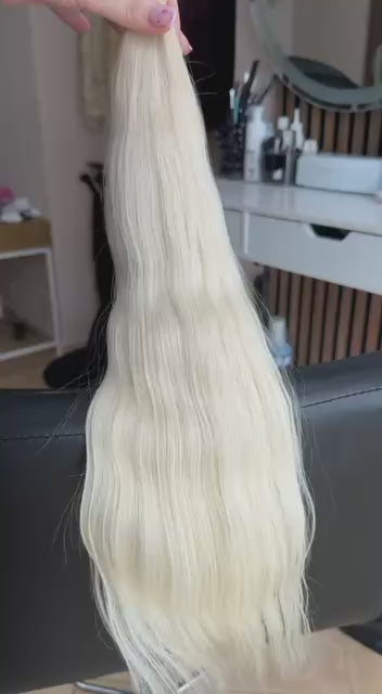 Video showing the flexibility and shine of a 50 cm (20 inch) premium raw Slavic wavy hair extension in cold-bleached blonde color