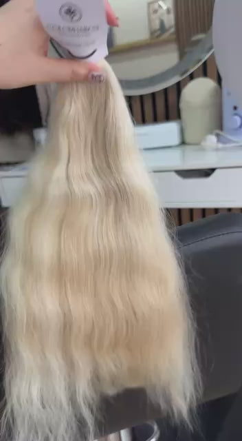 Video showing the flexibility and shine of a 50 cm (20 inch) premium raw Slavic wavy hair extension in cold-bleached Honey Blonde color