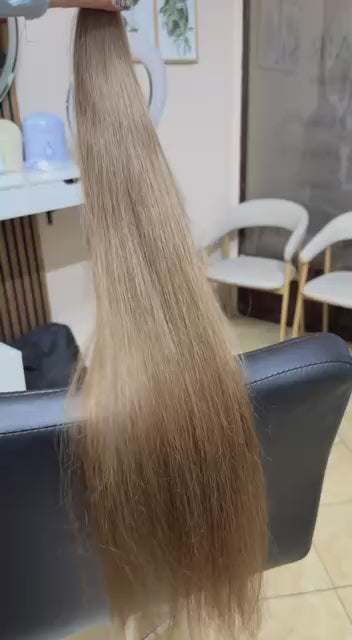 Video showing the flexibility and shine of a 70 cm (28 inch) premium raw Slavic wavy hair extension in cold-bleached Straight color