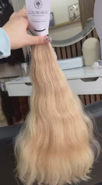 Video showing the flexibility and shine of a 45 cm (18 inch) premium raw Slavic wavy hair extension in cold-bleached Honey Blonde color