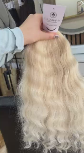 Video showing the flexibility and shine of a 40 cm (16 inch) premium raw Slavic wavy hair extension in cold-bleached Honey Blonde color