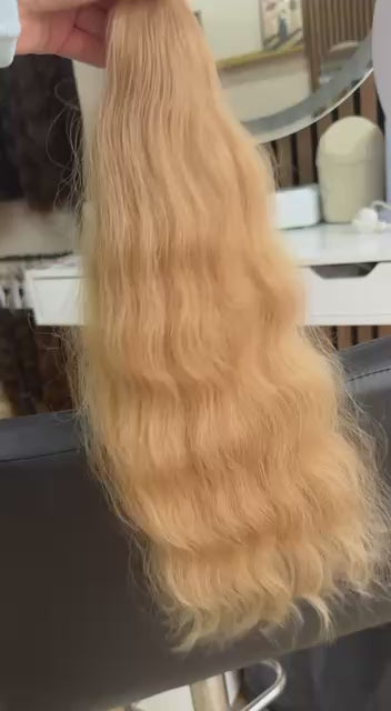 Video showing the flexibility and shine of a 50 cm (20 inch) premium raw Slavic wavy hair extension in cold-bleached Honey Blonde color