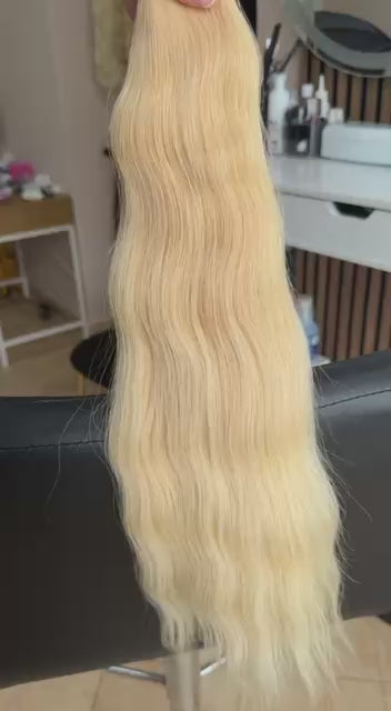 Video showing the flexibility and shine of a 55 cm (22 inch) premium raw Slavic wavy hair extension in cold-bleached Honey Blonde color