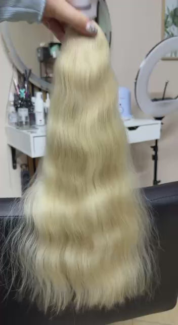 Video showing the flexibility and shine of a 50 cm (20 inch) premium raw Slavic wavy hair extension in cold-bleached blonde color