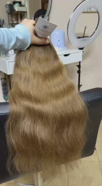Video showing the flexibility and shine of a 50 cm (20 inch) premium raw Slavic wavy hair extension in cold-bleached Honey Blonde color