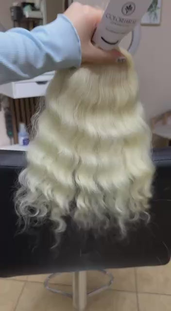 Video showing the flexibility and shine of a 40 cm (16 inch) premium raw Slavic wavy hair extension in cold-bleached blonde color