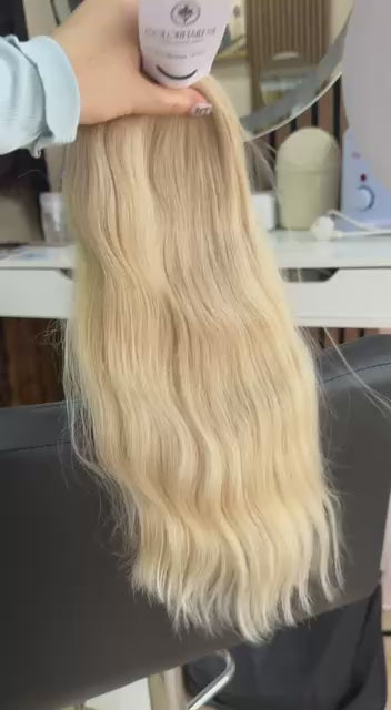 Video showing the flexibility and shine of a 45 cm (18 inch) premium raw Slavic wavy hair extension in cold-bleached Honey Blonde color