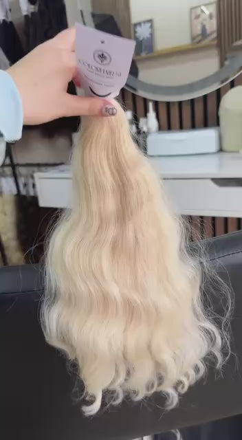 Video showing the flexibility and shine of a 40 cm (16 inch) premium raw Slavic wavy hair extension in cold-bleached blonde color