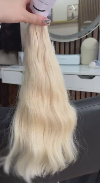 Video showing the flexibility and shine of a 45 cm (18 inch) premium raw Slavic wavy hair extension in cold-bleached Blonde color