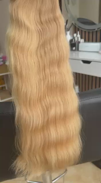 Video showing the flexibility and shine of a 55 cm (22 inch) premium raw Slavic wavy hair extension in cold-bleached Honey Blonde color