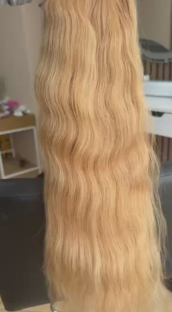 Video showing the flexibility and shine of a 55 cm (22 inch) premium raw Slavic wavy hair extension in cold-bleached Honey Blonde color