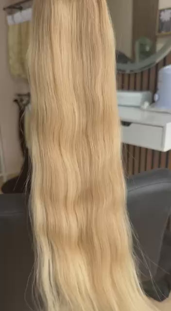 Video showing the flexibility and shine of a 60 cm (24 inch) premium raw Slavic wavy hair extension in cold-bleached Honey Blonde color